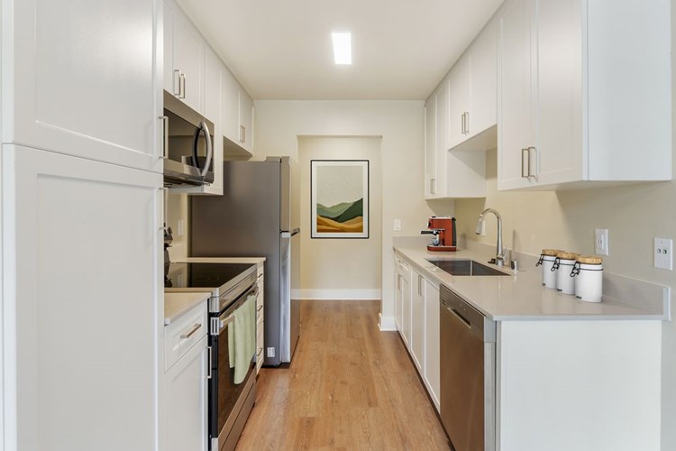 Renovated Package I kitchen with beige granite countertops, white cabinetry, stainless steel appliances, and hard surface flooring