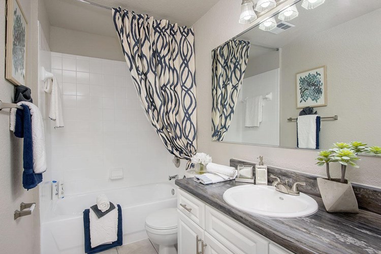 Newly remodeled bathrooms featuring black fusion counter tops, wood-style flooring, and large mirrors.