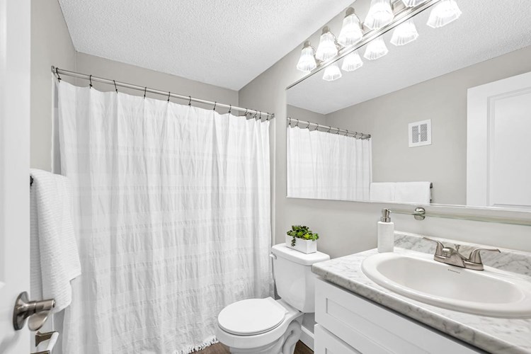 Newly remodeled bathrooms featuring wood-style flooring and marble-style counter tops. 