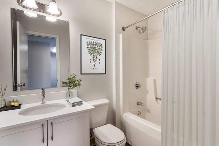 Renovated Package I bath with white laminate countertops, white cabinetry, and hard surface flooring