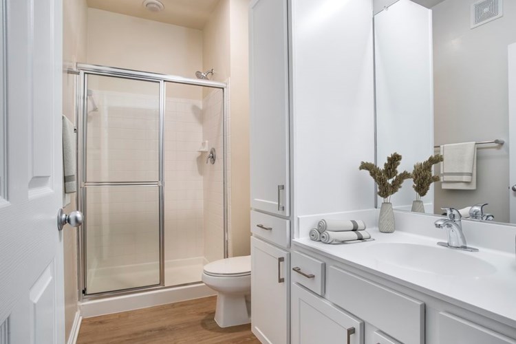 Renovated Package II bath with white countertops, white cabinetry, and hard surface flooring