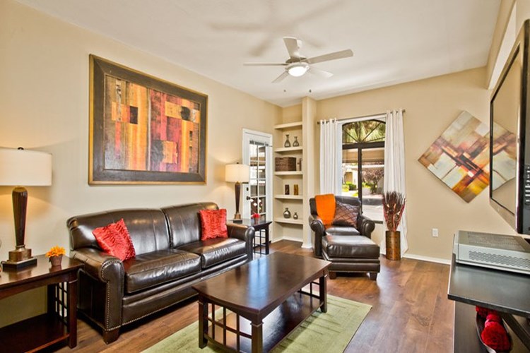Spacious living room featuring ceiling fan and wood flooring available in select apartments