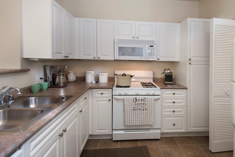 Classic Package I kitchen with white cabinetry, white appliances, laminate countertops, and tile flooring