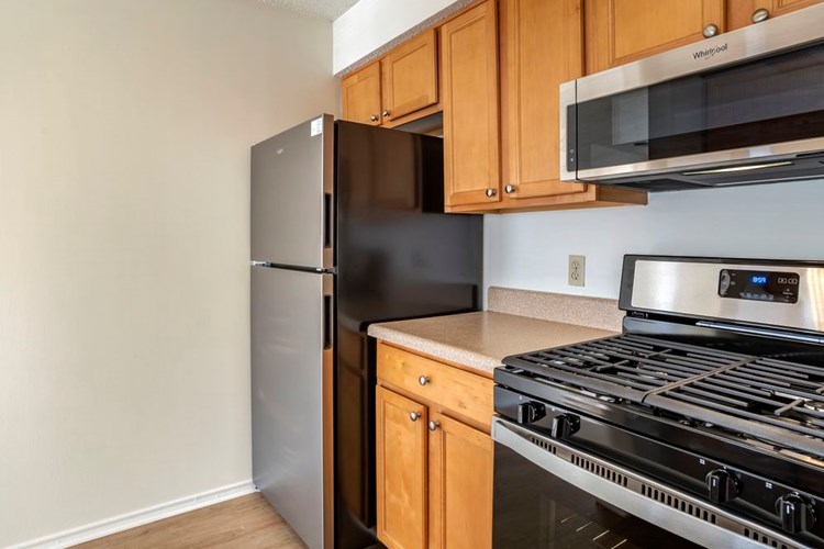 Renovated Package I kitchen with stainless steel appliances, laminate countertops, oak cabinetry, and hard surface flooring