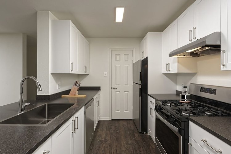 Renovated Package II kitchen with white cabinetry, dark grey laminate countertops, and stainless steel appliances, and hard surface plank flooring