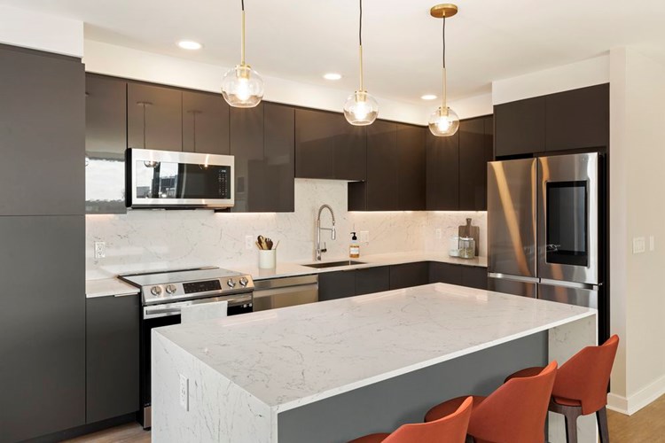 Renovated Package I kitchen with grey cabinetry, white marbled quartz countertops and backsplash, stainless steel appliances, and hard surface flooring