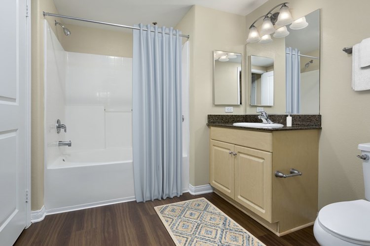 Classic Package I bath with brown speckled granite countertops, oak cabinetry, and hard surface flooring