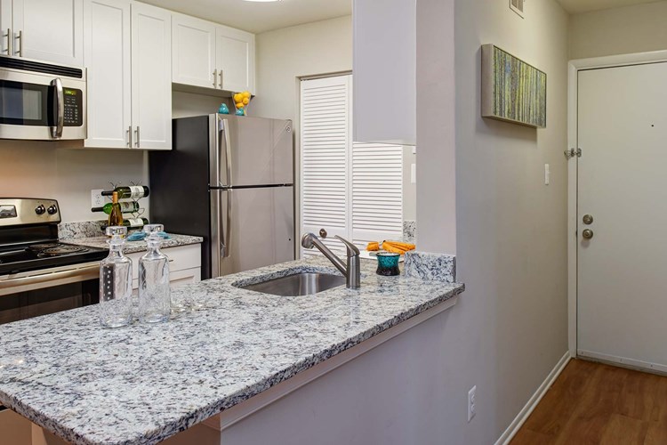 Modern kitchen features stainless steel appliances, granite countertops in select homes
