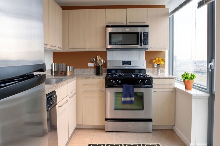 Classic Package I kitchen with beige speckled countertops, beige cabinets, stainless steel appliances, and hard surface flooring