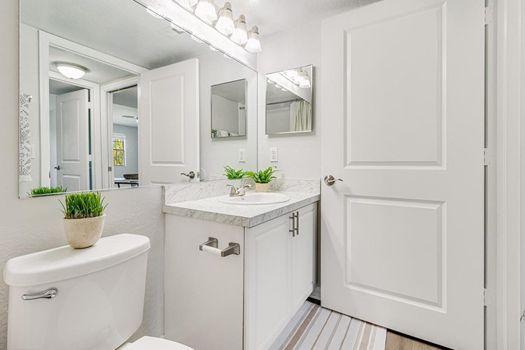 Updated bathrooms featuring wood-style flooring and large mirrors.