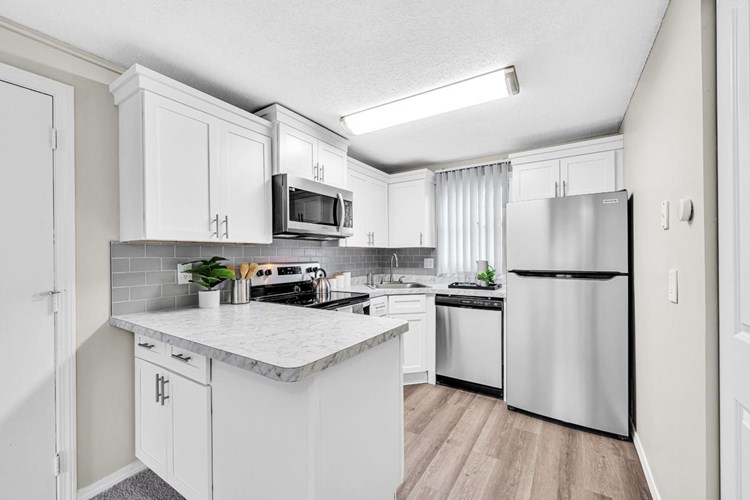 Newly renovated kitchens featuring Carrara marble counter tops, wood-style flooring, and stainless-steel appliances.