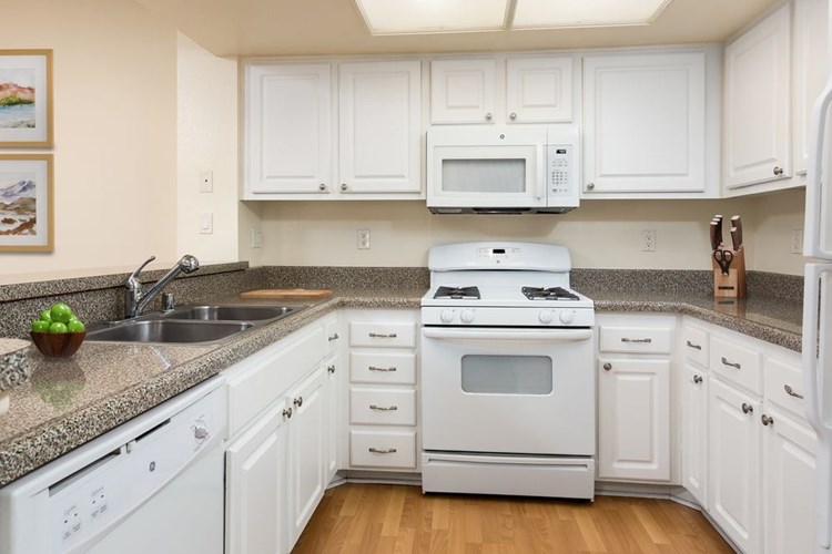 Classic Package I kitchen with white appliances, faux granite countertops, white shaker cabinetry, and hard surface flooring