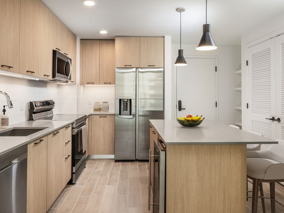 Kitchen with stainless steel appliances, grey quartz countertops, white tile backsplash, and hard surface flooring