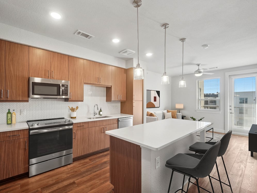 Finish Package I kitchen with stainless steel appliances, dark cabinetry, white tile backsplash, white quartz countertops, and hard surface flooring
