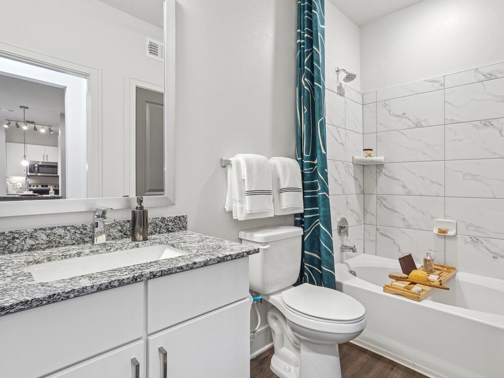 Bath with white cabinetry, speckled granite countertops, and hard surface flooring