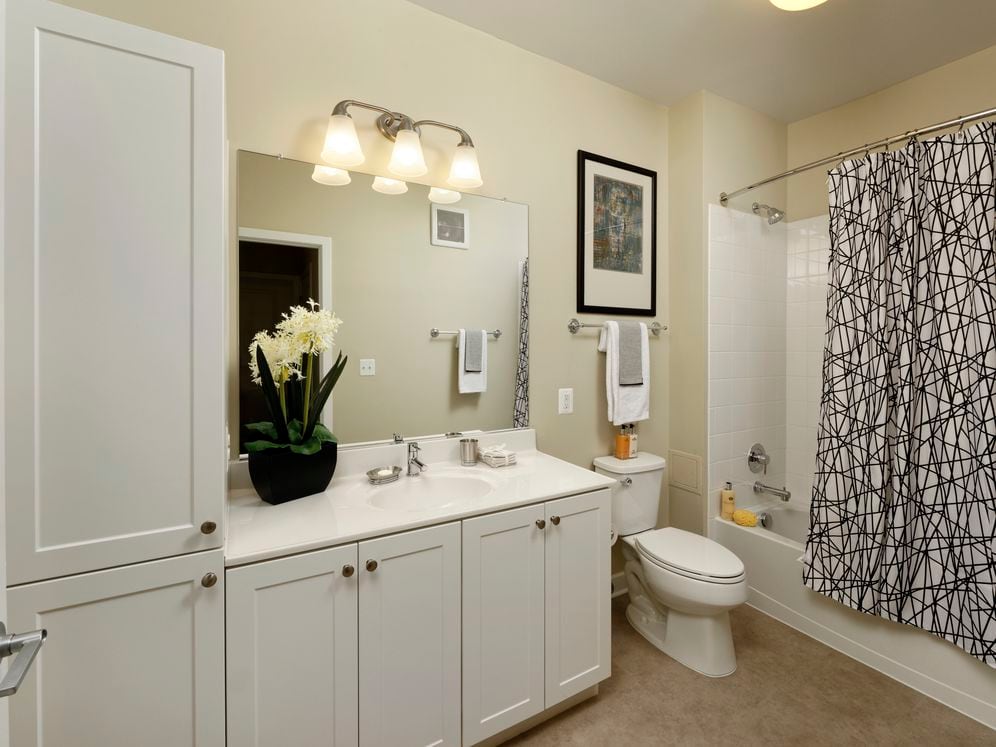 Bathroom with white shaker cabinetry, white countertop, shower and bath with white tile backsplash and hard surface flooring