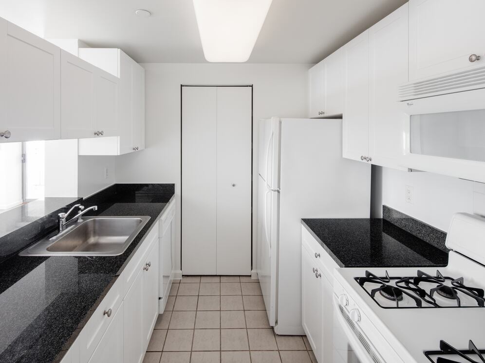 Classic Package I kitchen with white appliances, white cabinetry, black granite countertops, and tile flooring