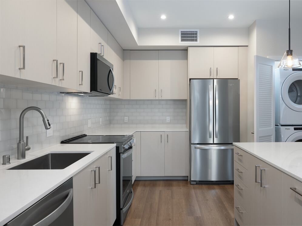 Upgrade Collection Apartment kitchen featuring light cabinetry, white tile backsplash, pendant lighting, white quartz countertops, and hard-surface vinyl plank flooring