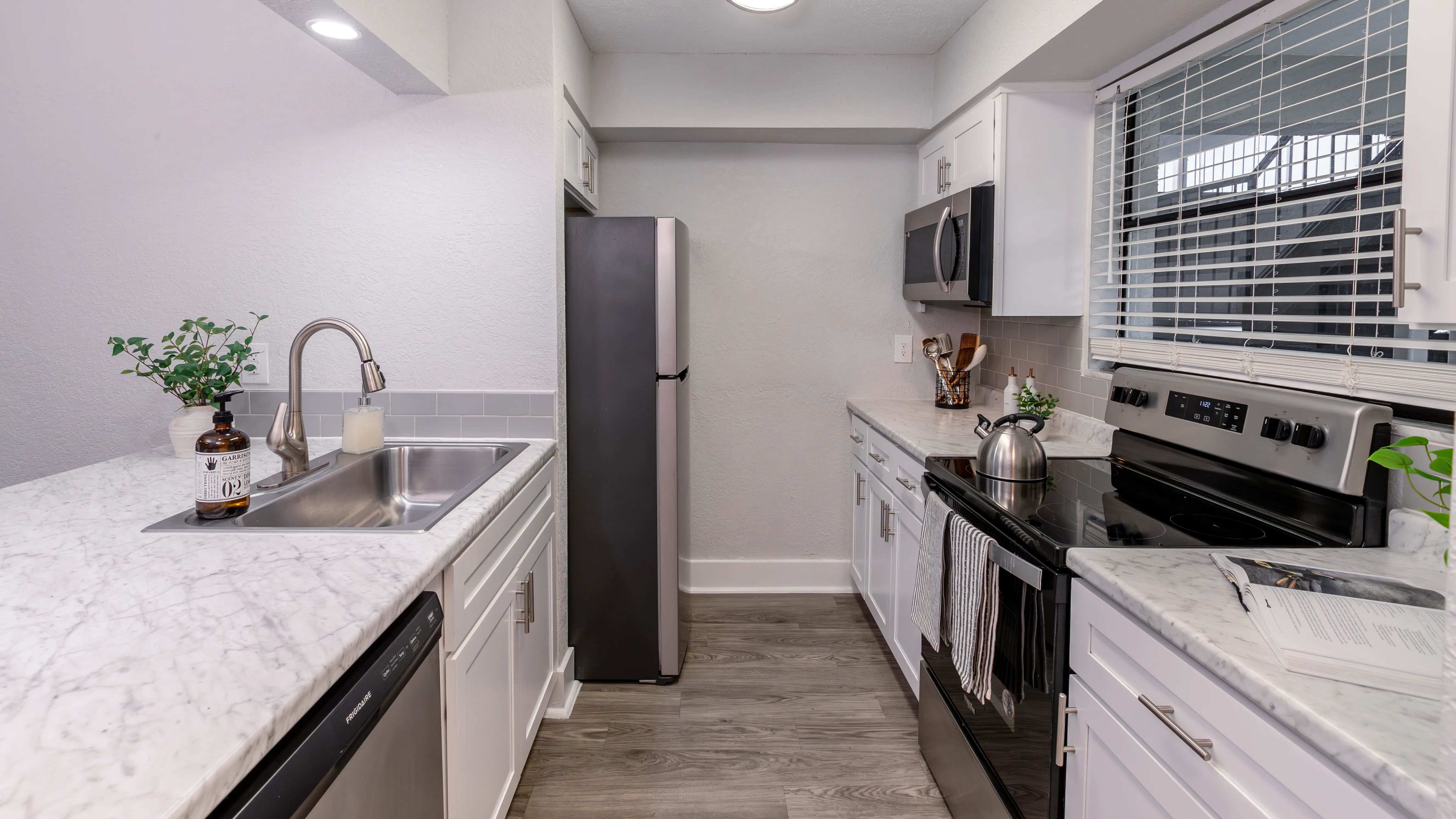 Experience the elegance of a modern kitchen featuring stainless steel appliances, marble-style countertops, and a sleek tile backsplash.