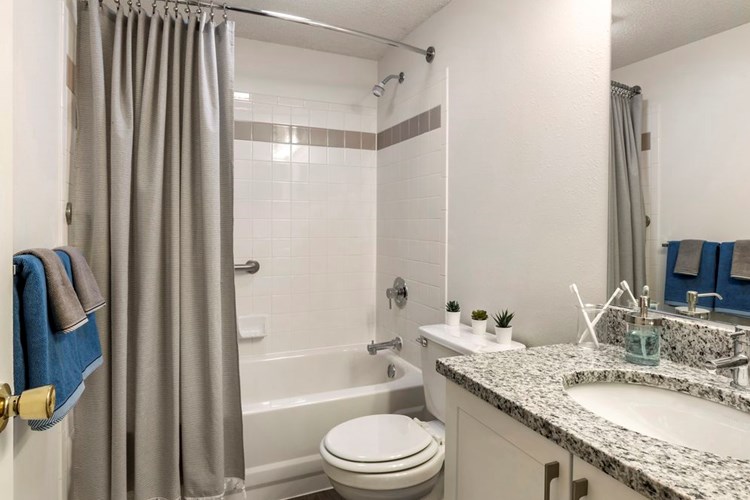 Renovated Package II bath with white cabinetry, quartz countertops, and hard surface flooring
