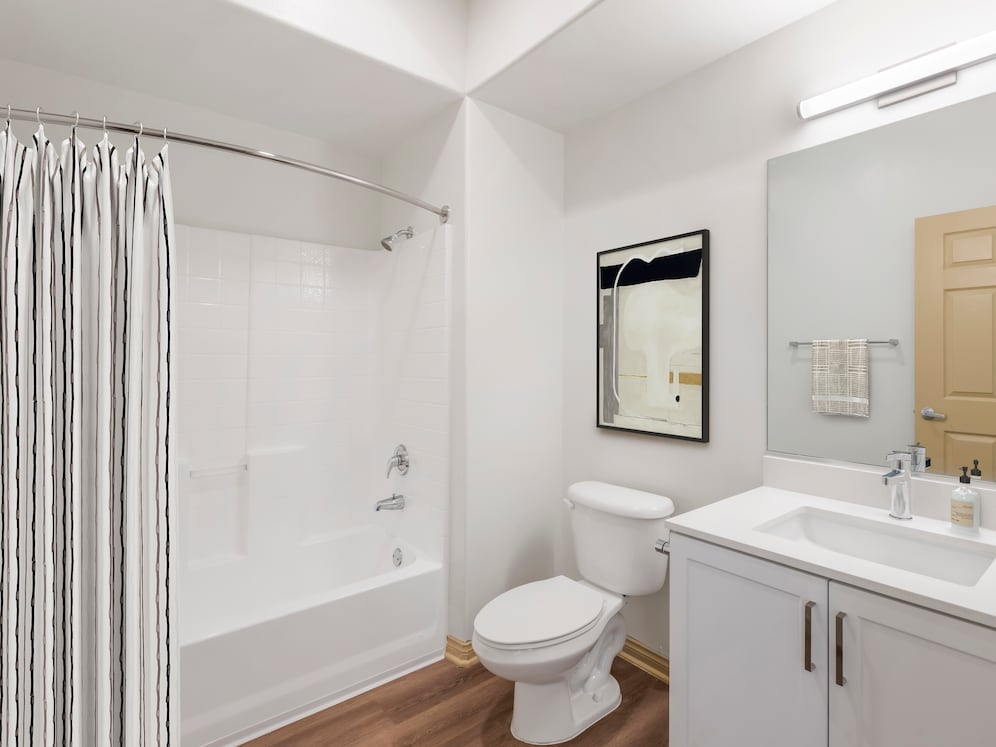 Renovated Package I bath with white speckled quartz countertop, white cabinetry, and hard surface flooring