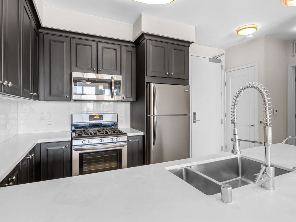 Kitchens with dark cabinetry, white quartz countertops, white tile backsplash, stainless steel appliances, and hard surface flooring