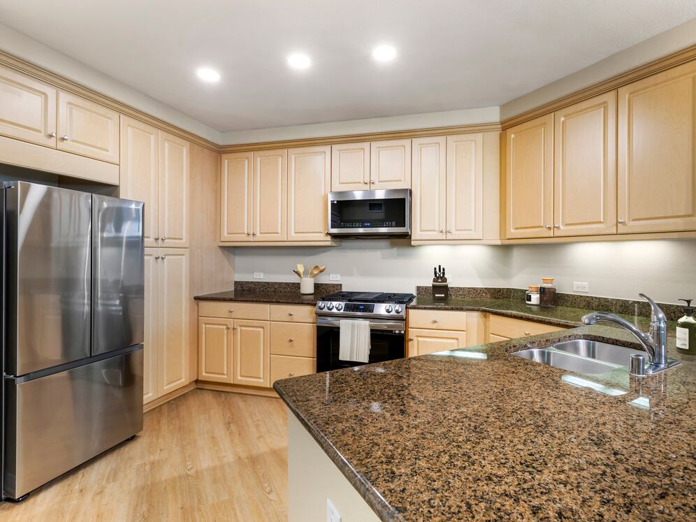 Classic Package II kitchen with stainless steel appliances, brown speckled granite, oak cabinetry, and hard surface flooring