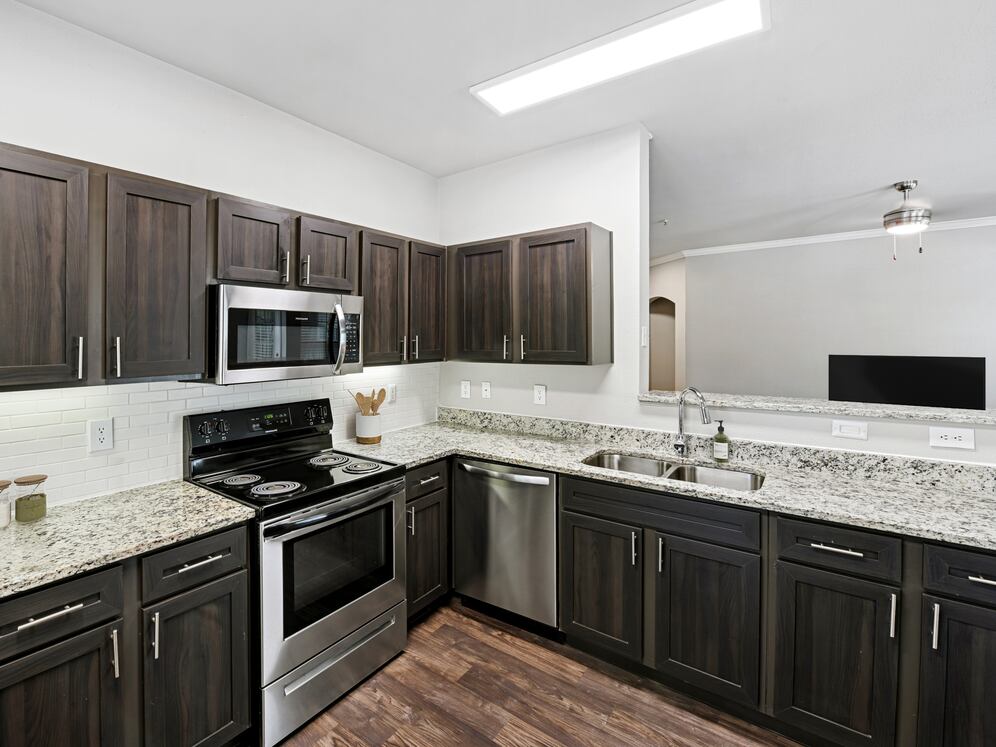 Classic Package II kitchen with stainless steel appliances, espresso cabinetry, white subway tile backsplash, speckled granite countertops, and hard surface flooring