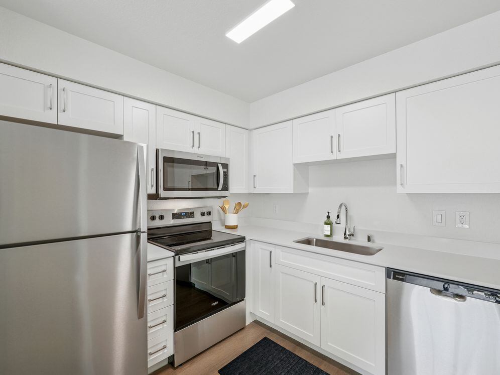 Upgraded Collection kitchen with stainless steel appliances, updated white cabinetry, quartz countertops, and hard surface flooring