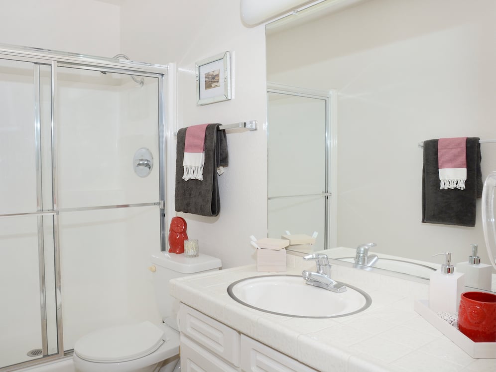 Classic Package bath featuring white tile countertops and white cabinetry