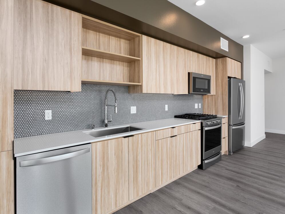 Open concert kitchen with quartz countertops backsplash, stainless steel appliances and hard surface flooring