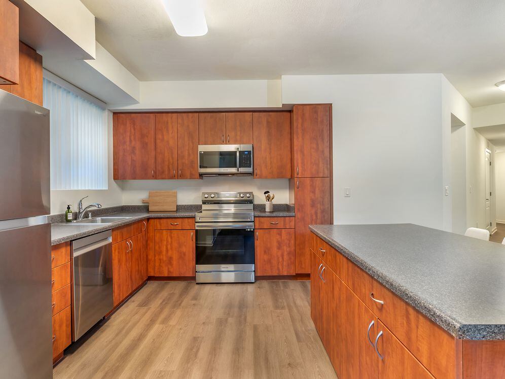 Classic Package II kitchen with stainless steel appliances, grey laminate countertops, cherry cabinetry, and hard surface flooring