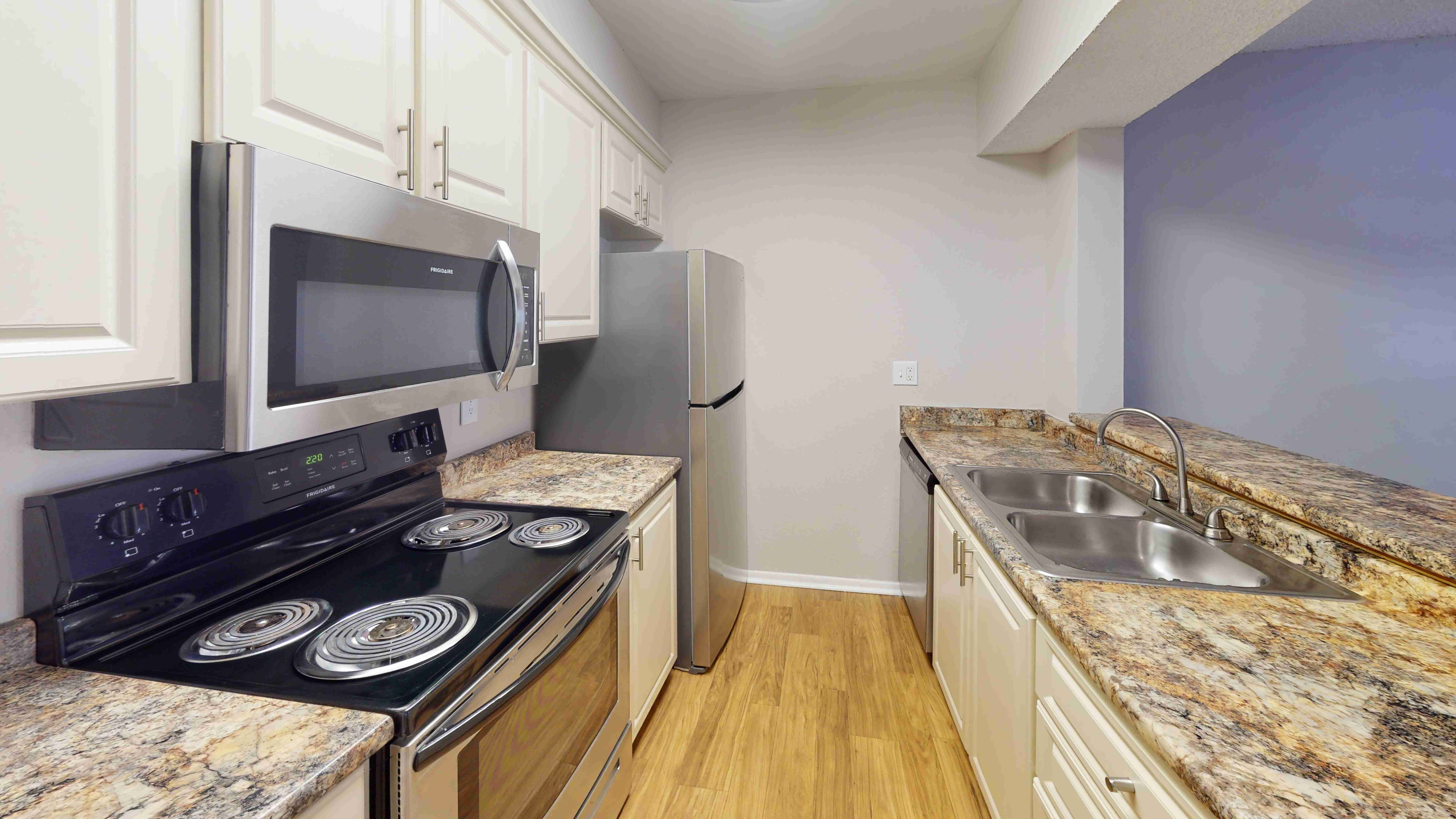 The kitchen in The Oakwood floor plan features stainless steel appliances, granite-style countertops, ample cabinetry, and generous countertop space. The layout connects the kitchen to the living area, making everyday cooking and entertaining effortless.