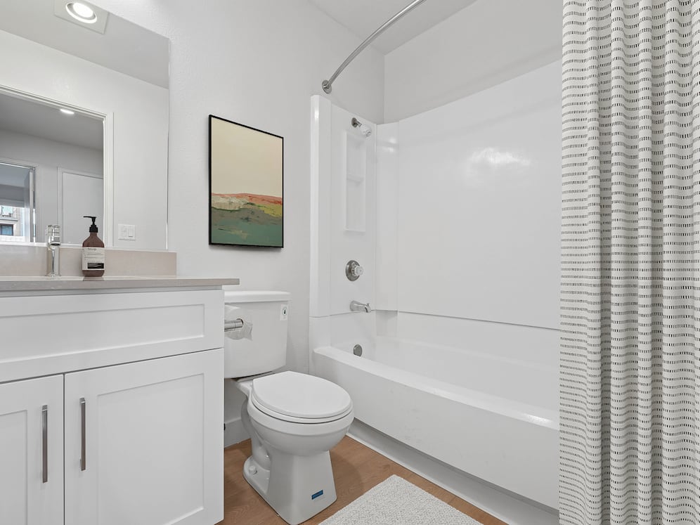 Renovated Package I bath with white cabinetry, grey quartz countertops, and hard surface flooring