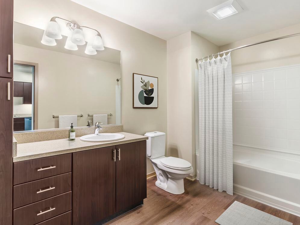 Updated Finishes bath with grey speckled granite countertop, espresso cabinetry, and hard surface flooring