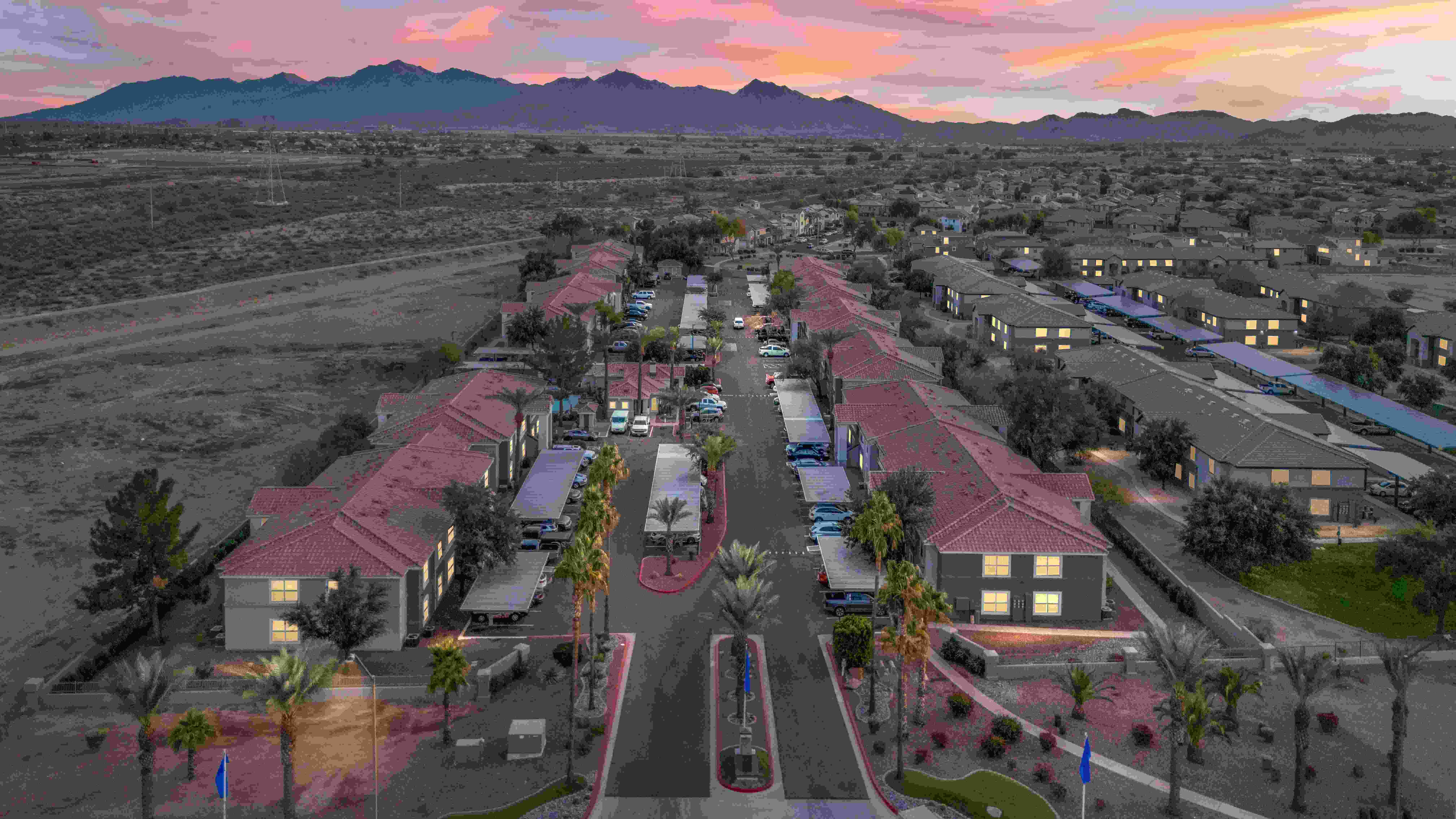 Aerial view of Sedona Peaks apartment community at twilight, showcasing desert landscape, mountain views, and well-lit residential buildings.
