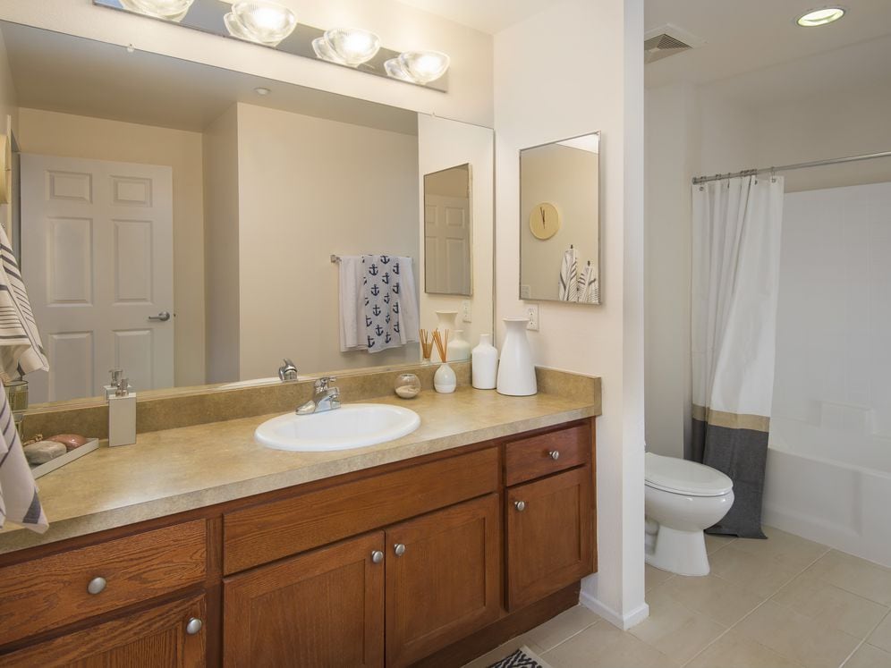 Classic Package I master bath with maple cabinetry, beige speckled granite countertops, and tile flooring