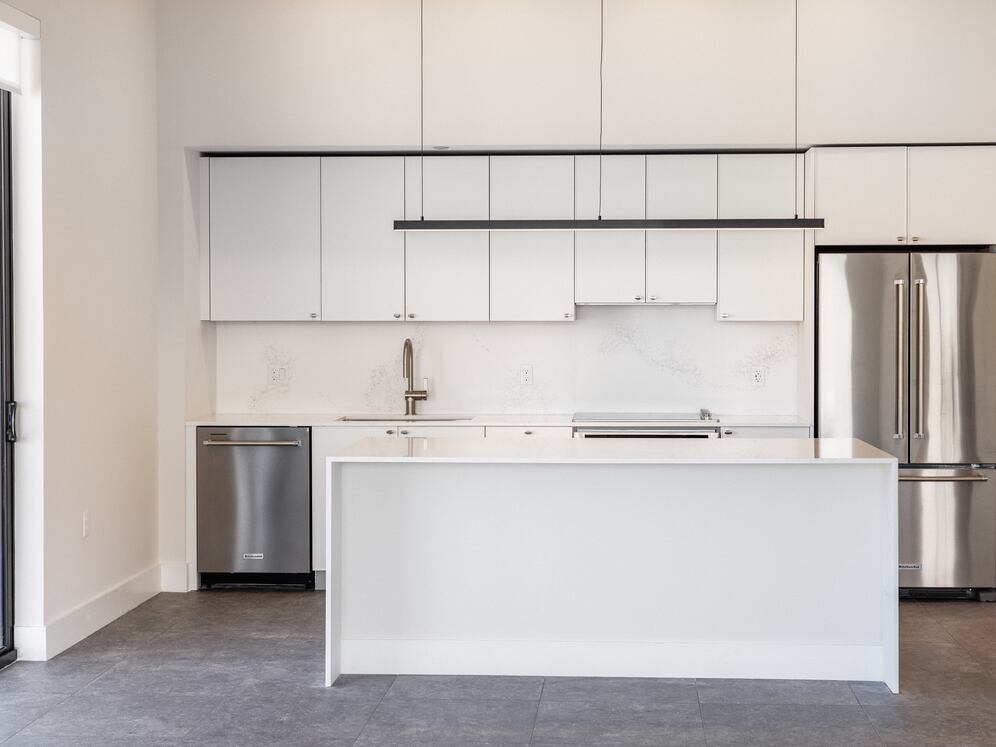 Signature Collection kitchen with white cabinetry, white marbled quartz countertop and backsplash, wine fridge, and upgraded stainless steel appliances