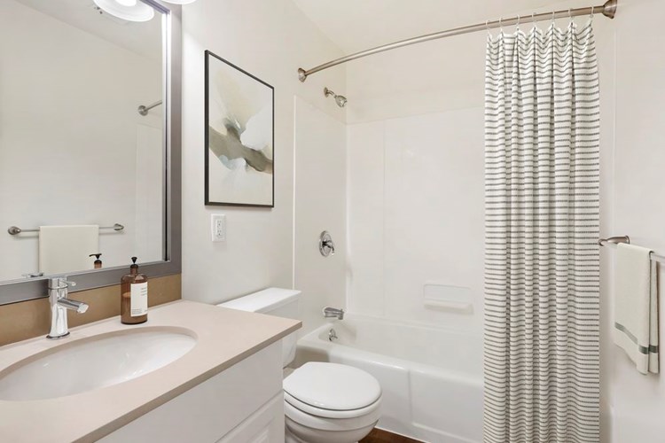 Renovated Package III bath with grey quartz countertops, white or cherry cabinetry, and hard surface flooring