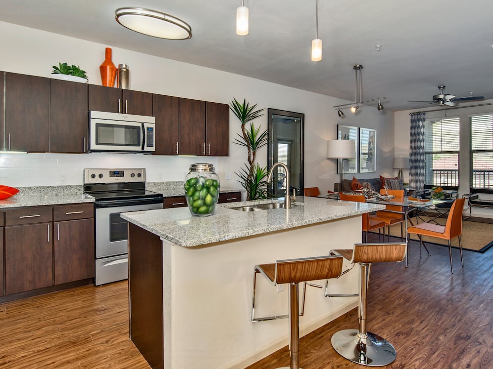 Classic Package I kitchen with espresso cabinetry, speckled granite countertops, white subway tile backsplash, stainless steel appliances, and hard surface flooring