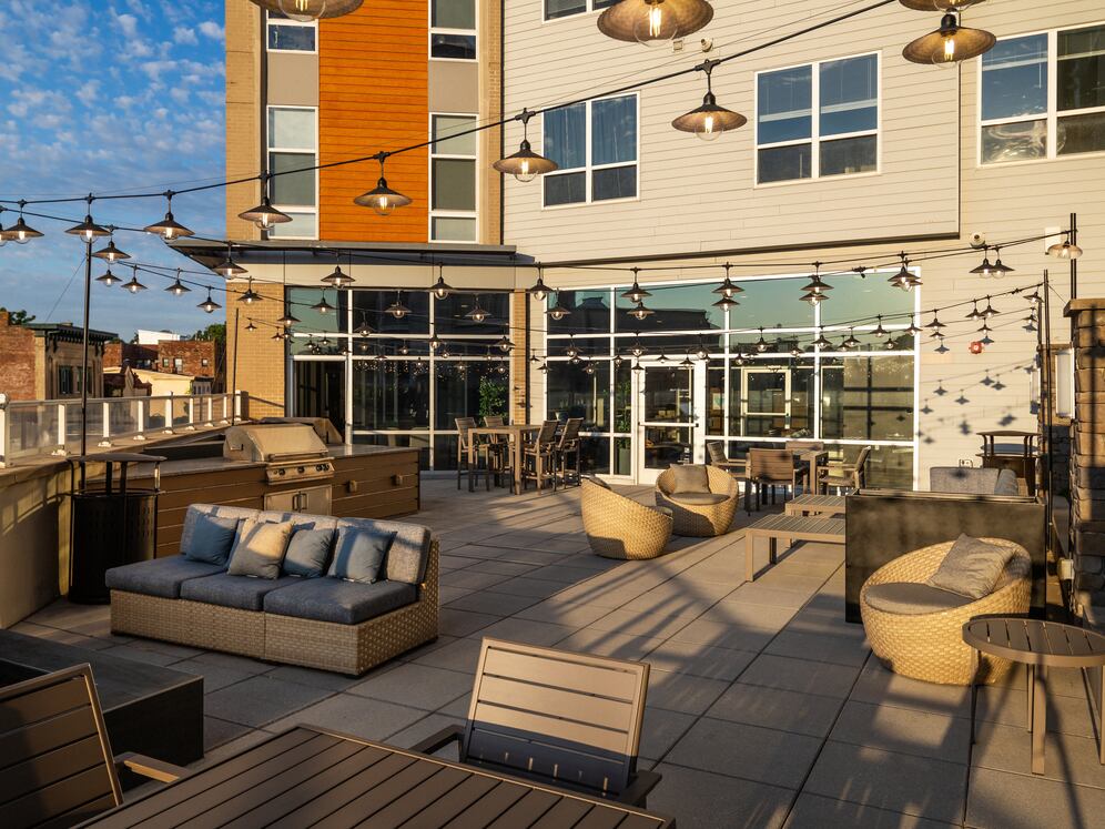 Rooftop patio with BBQ grills, lounge seating, and firepit