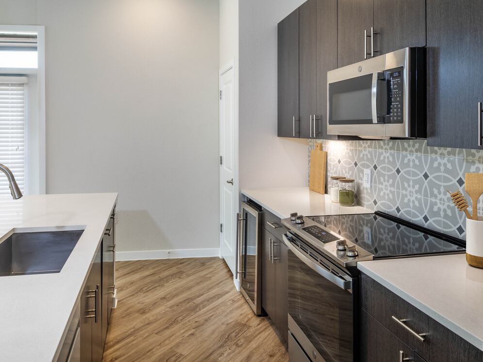 Kitchens with stainless steel appliances, wine fridges, quartz countertops, tile backsplash, and hard surface flooring