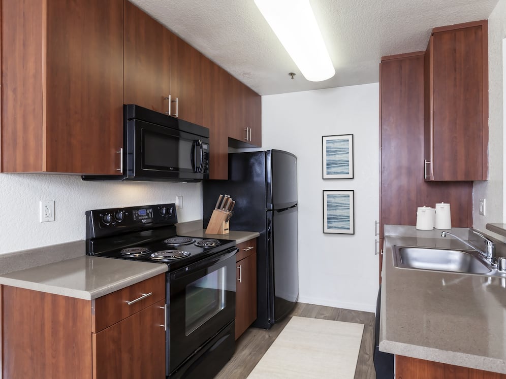 Classic Package kitchen with black appliances, dark grey laminate countertops, cherry cabinetry,  and hard surface flooring