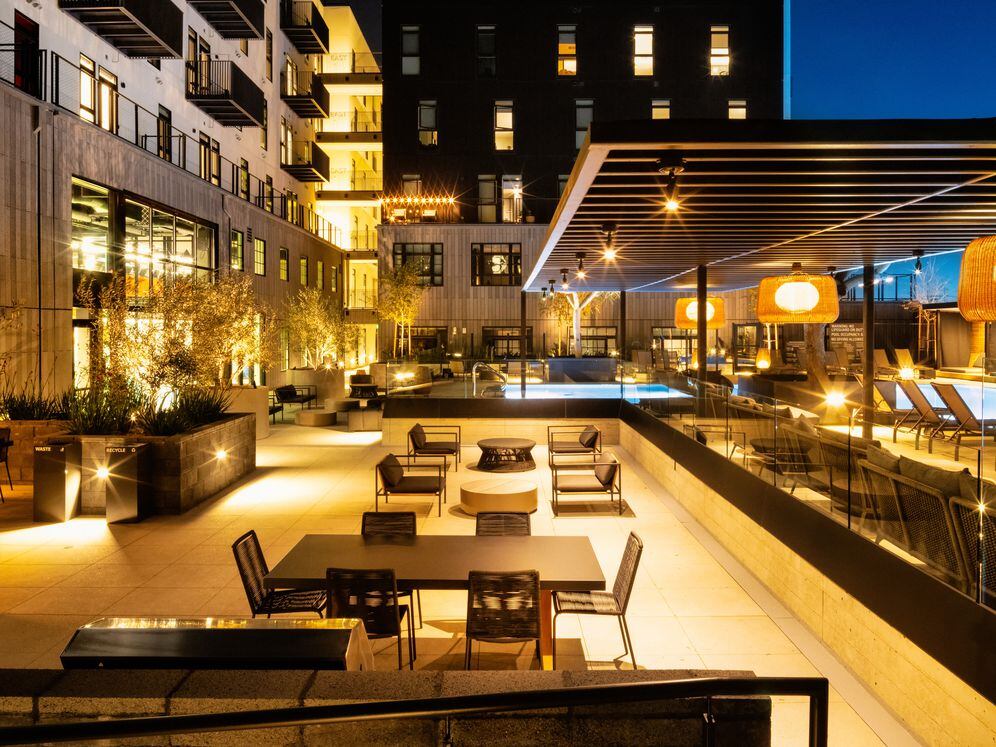 Poolside courtyard with dining tables, seating, and grills