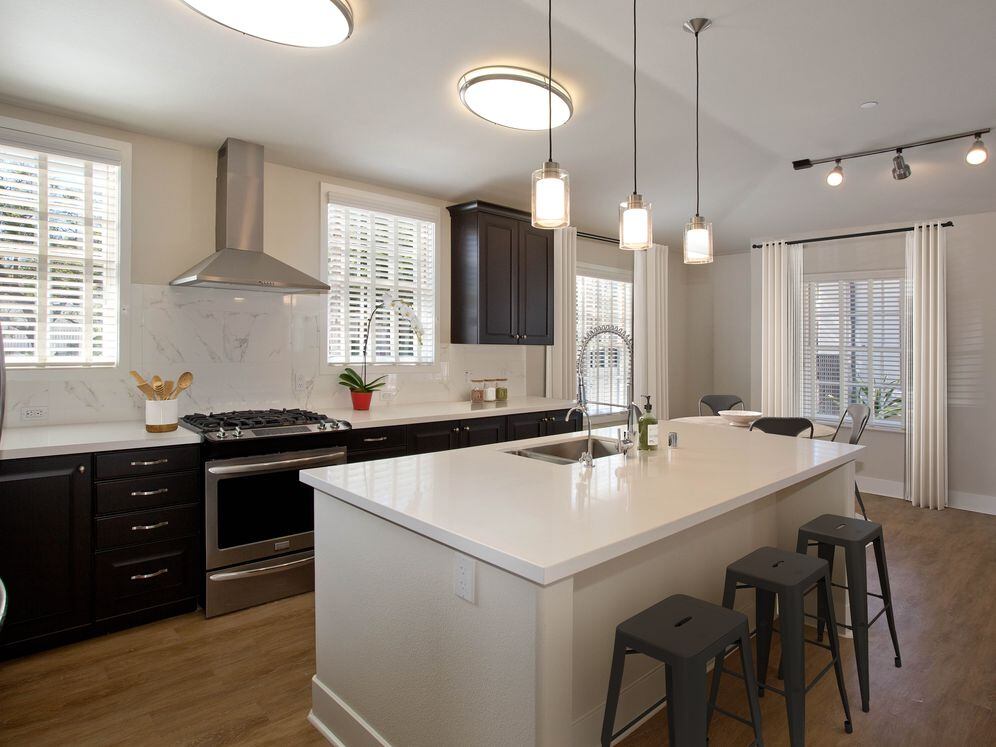 Kitchens with dark cabinetry, white quartz countertops, white tile backsplash, stainless steel appliances, and hard surface flooring