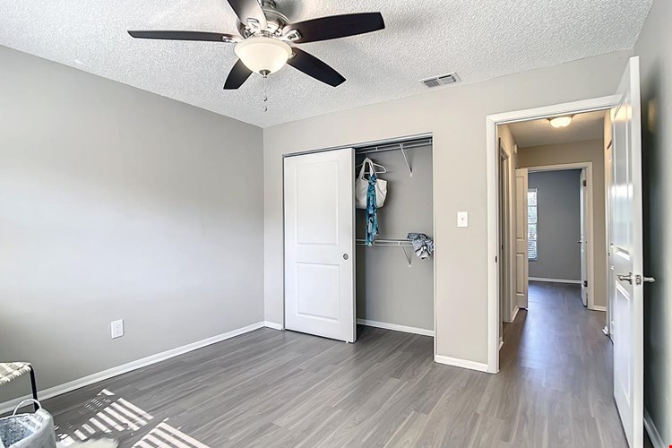 Bedrooms feature wood-style flooring, spacious closets, and a multi-speed ceiling fan.