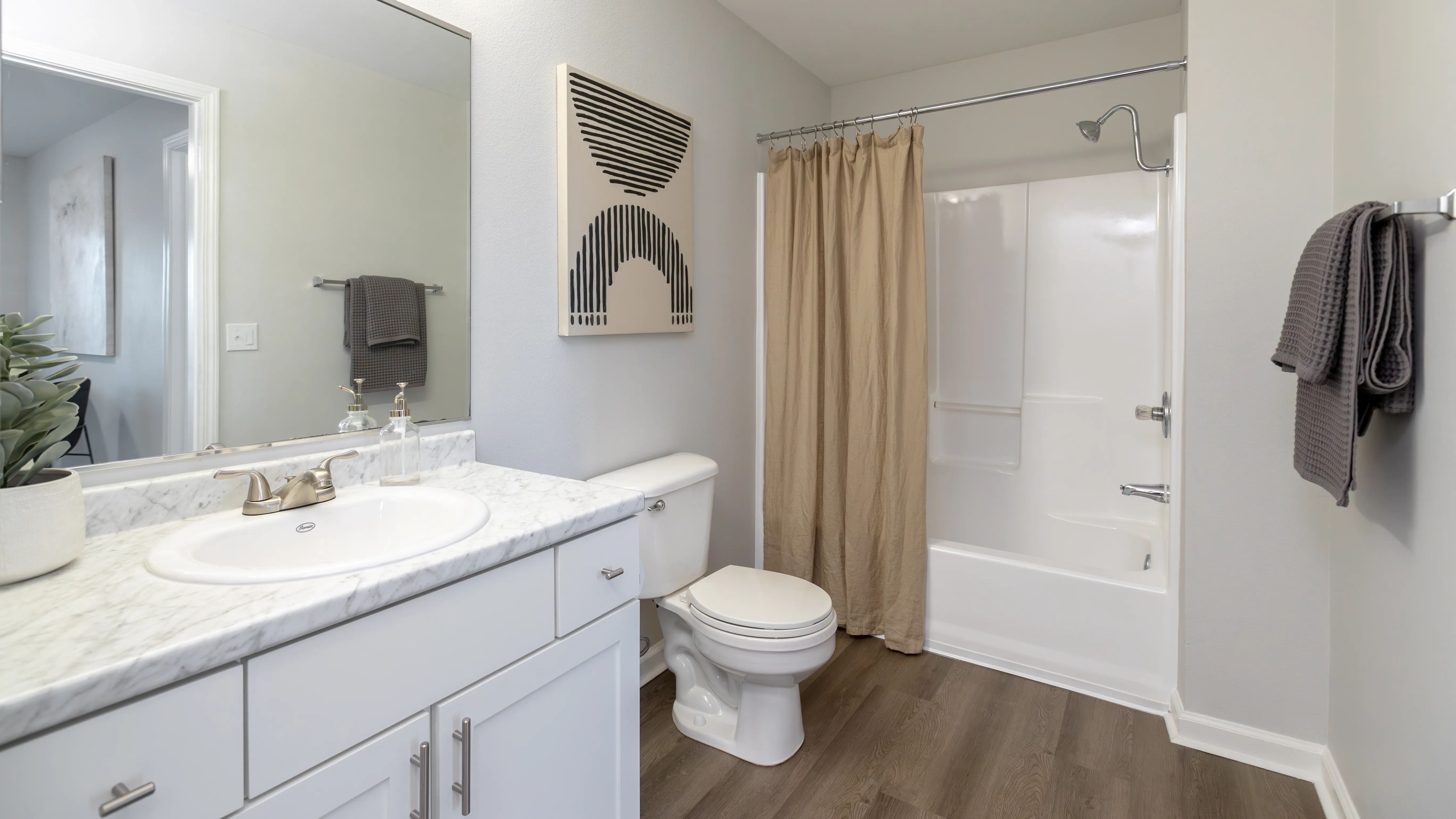 Pamper yourself with the expansive master bathroom's oversized vanity and mirror and enjoy elegant wood-style flooring. 