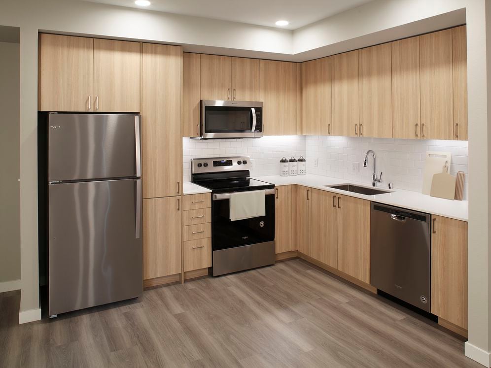 Phase II - Scheme D Kitchen with oak cabinetry, white tile backsplash, stainless steel appliances, white quartz countertops, and hard surface flooring