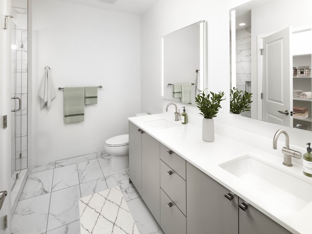 Signature Collection Townhome bathroom with grey cabinetry, white quartz countertop, lighted vanity mirrors, porcelain shower surround, and porcelain tile flooring