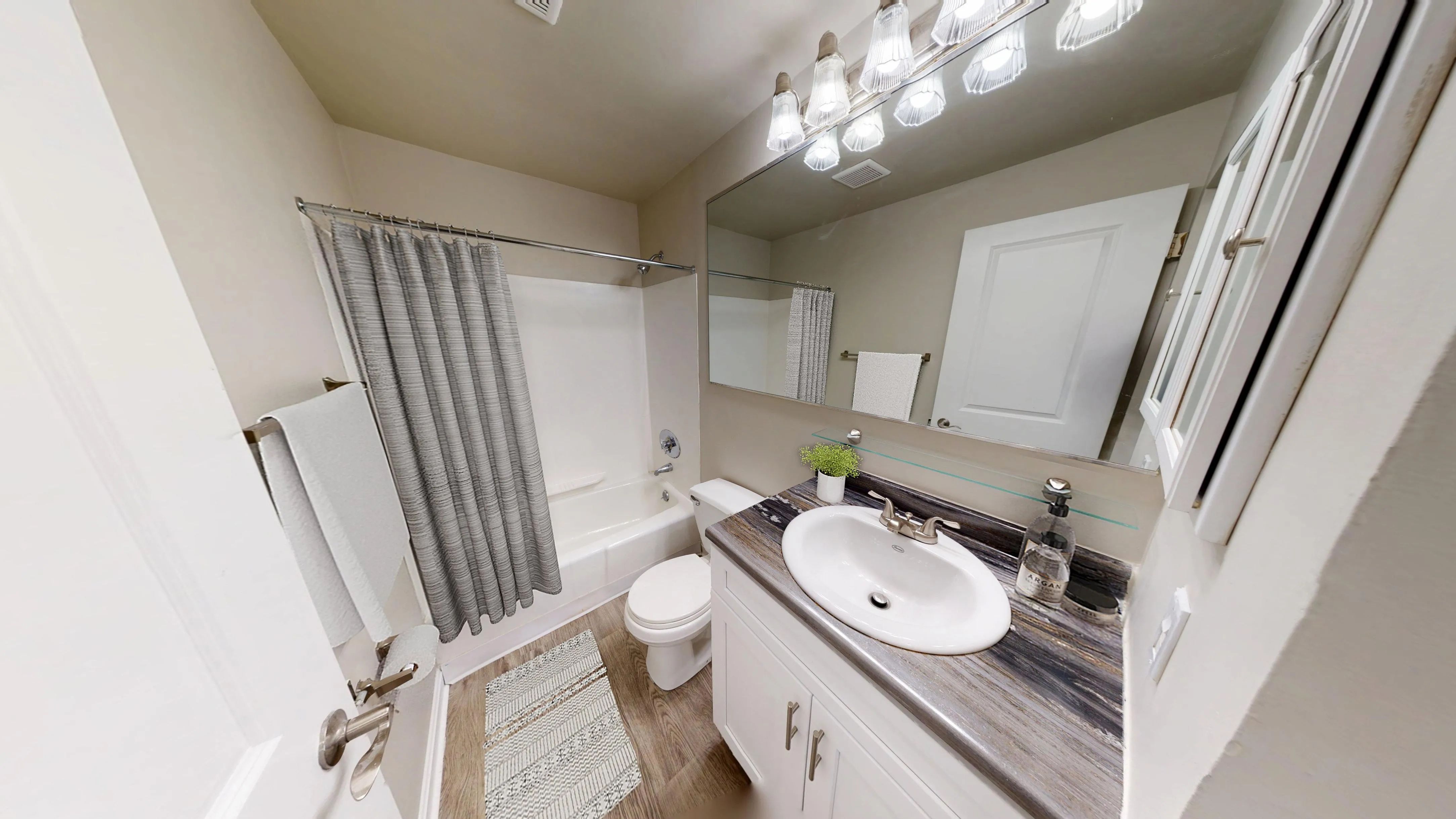 The Dickenson floor plan features a bright and updated bathroom with a large mirror, modern vanity, and wood-style flooring.